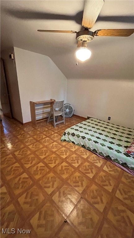 unfurnished bedroom featuring ceiling fan, parquet flooring, and vaulted ceiling