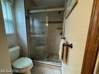 bathroom with toilet, an enclosed shower, and tile patterned floors