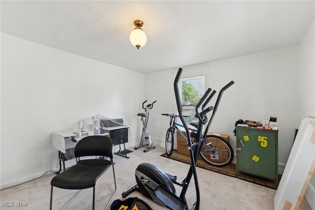 workout area featuring light carpet and a textured ceiling