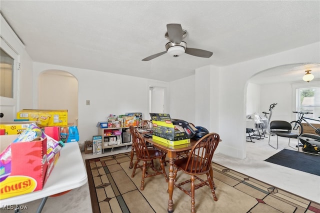 carpeted dining room with a textured ceiling and ceiling fan