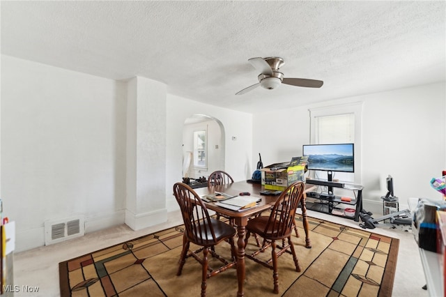 carpeted dining space with ceiling fan and a textured ceiling