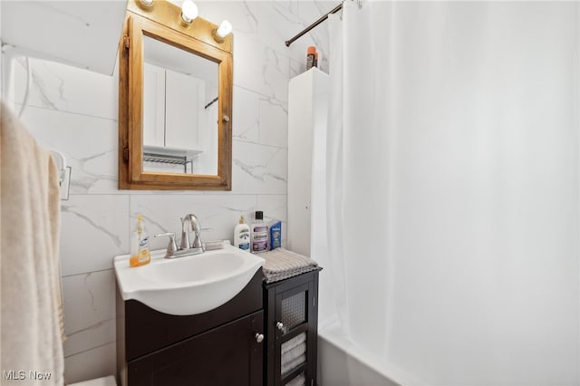 bathroom featuring shower / bath combo, tile walls, and vanity