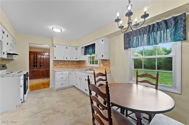 kitchen featuring a healthy amount of sunlight, white range with electric stovetop, an inviting chandelier, and white cabinets