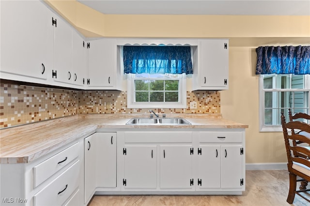 kitchen featuring decorative backsplash, white cabinetry, and sink