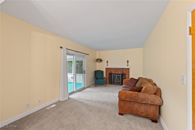 living area with a brick fireplace and carpet