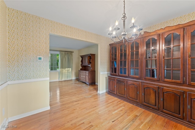 unfurnished dining area featuring light hardwood / wood-style flooring and an inviting chandelier