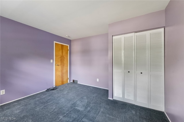 unfurnished bedroom featuring a closet and dark colored carpet