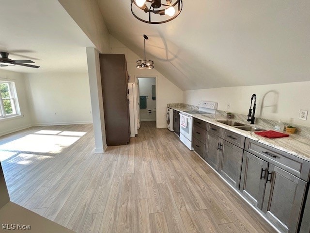 kitchen with white electric range oven, light wood-type flooring, vaulted ceiling, sink, and light stone counters