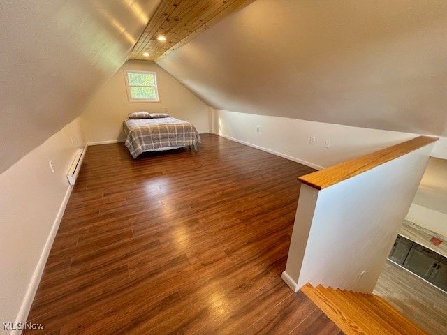 unfurnished bedroom with vaulted ceiling, a baseboard heating unit, and dark hardwood / wood-style flooring