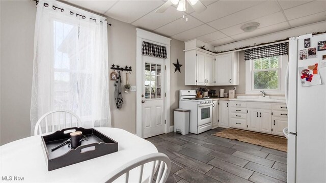 kitchen featuring white appliances, dark wood-type flooring, a paneled ceiling, ceiling fan, and white cabinets