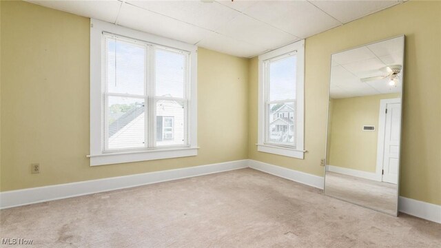 unfurnished room with a wealth of natural light, ceiling fan, and light carpet