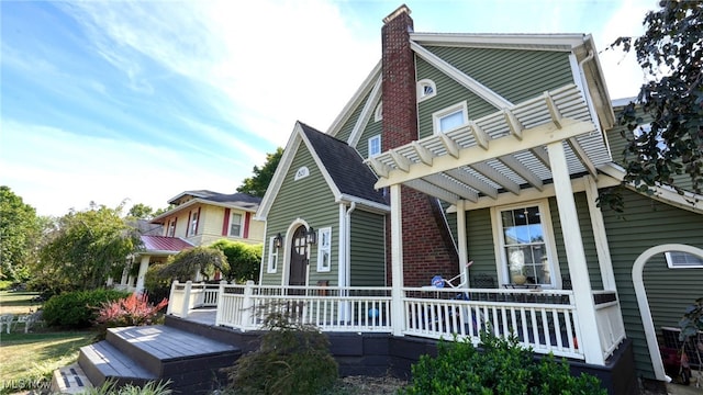 rear view of property featuring a pergola and a deck