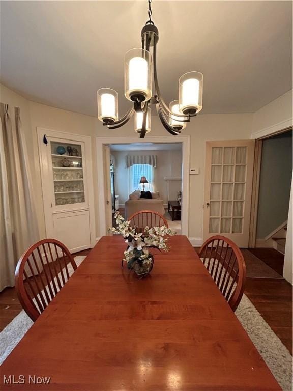 dining room featuring an inviting chandelier, stairway, built in features, and wood finished floors