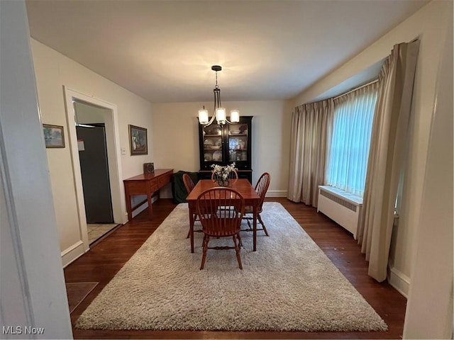 dining area featuring radiator, dark wood-style flooring, and an inviting chandelier