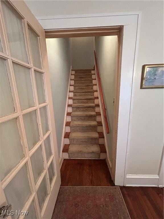 staircase featuring baseboards and wood finished floors