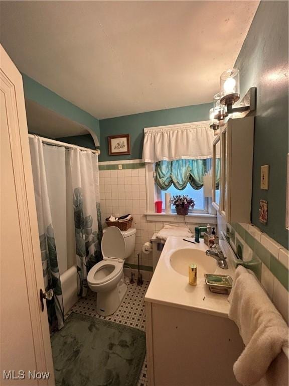 bathroom featuring toilet, vanity, tile walls, wainscoting, and radiator heating unit