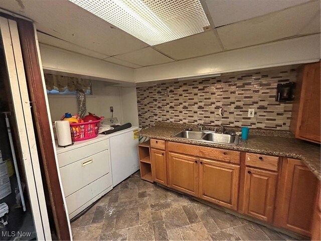 kitchen featuring a paneled ceiling, independent washer and dryer, sink, and backsplash