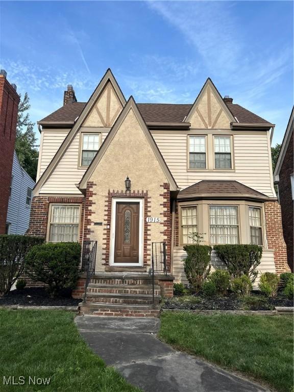 view of front of home with a chimney and brick siding