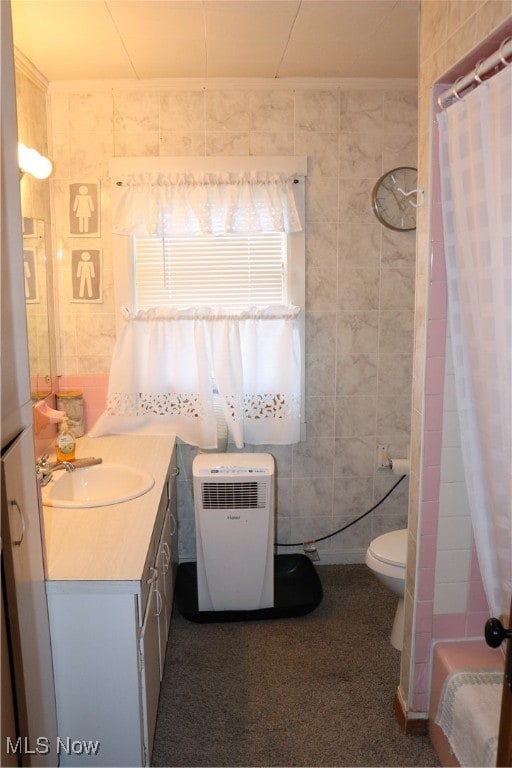 bathroom with vanity, toilet, and tile walls