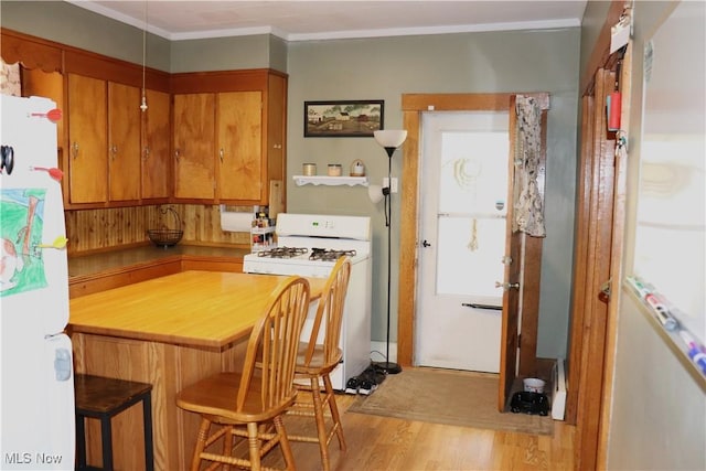 kitchen with white appliances, brown cabinetry, ornamental molding, a breakfast bar area, and light wood-type flooring