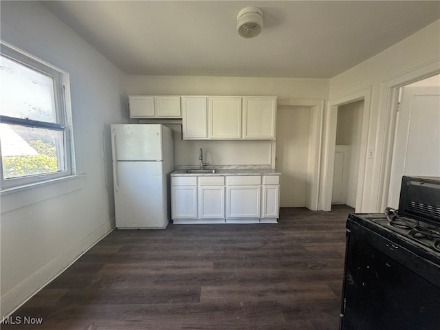 kitchen featuring white fridge, gas stove, white cabinetry, and sink