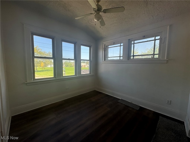 unfurnished room with dark wood-type flooring, a textured ceiling, a healthy amount of sunlight, and ceiling fan