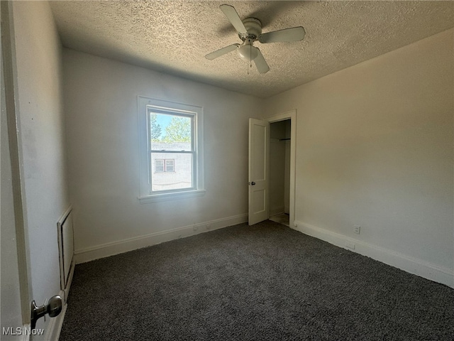 carpeted spare room featuring a textured ceiling and ceiling fan