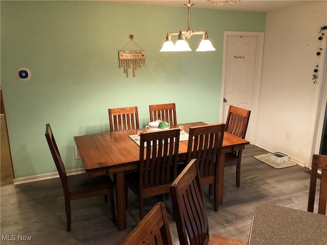 dining area with dark wood-type flooring and a chandelier