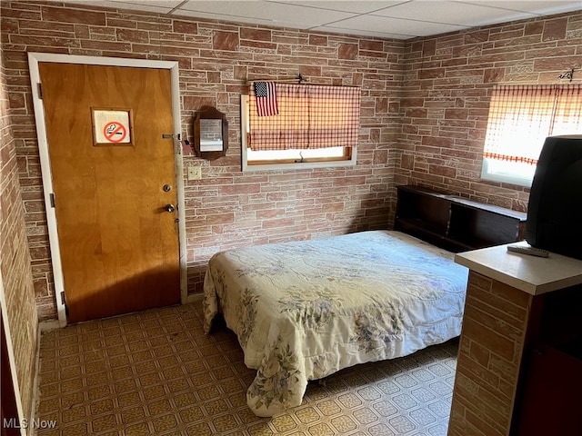 bedroom with brick wall and a drop ceiling