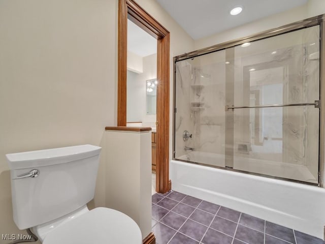 bathroom featuring tile patterned flooring, enclosed tub / shower combo, vanity, and toilet