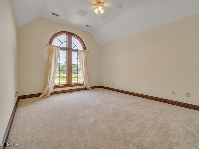 carpeted spare room featuring baseboards, visible vents, and vaulted ceiling