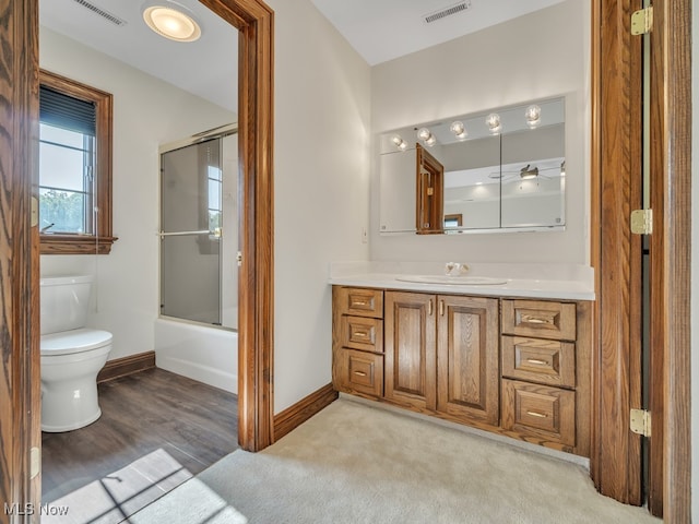 full bathroom featuring vanity, toilet, hardwood / wood-style flooring, and enclosed tub / shower combo