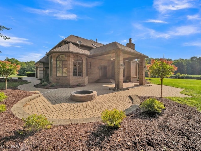 rear view of property with an outdoor fire pit, brick siding, a patio, and a chimney