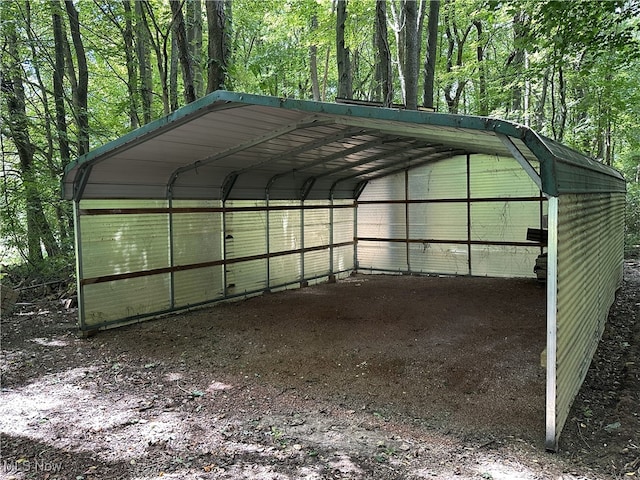 exterior space with a detached carport and a view of trees