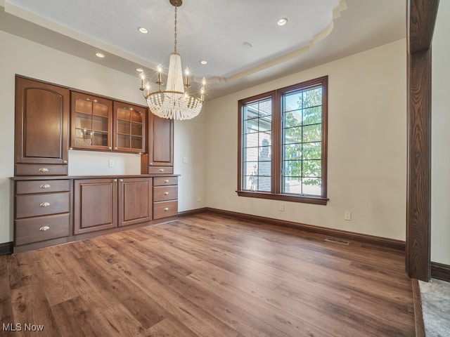 kitchen with dark wood-type flooring, a chandelier, pendant lighting, and a raised ceiling