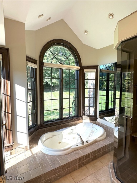 bathroom featuring lofted ceiling, tiled bath, and tile patterned floors