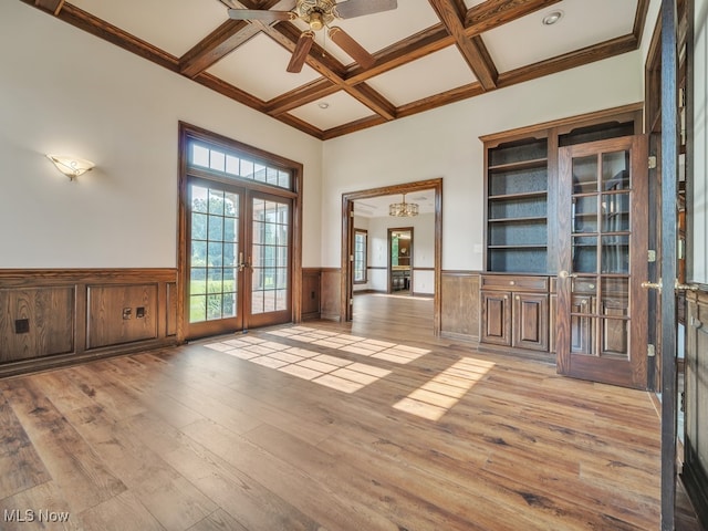 empty room featuring coffered ceiling, beam ceiling, french doors, light hardwood / wood-style floors, and ceiling fan