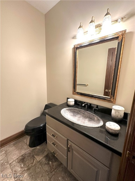 bathroom featuring baseboards, vanity, and toilet