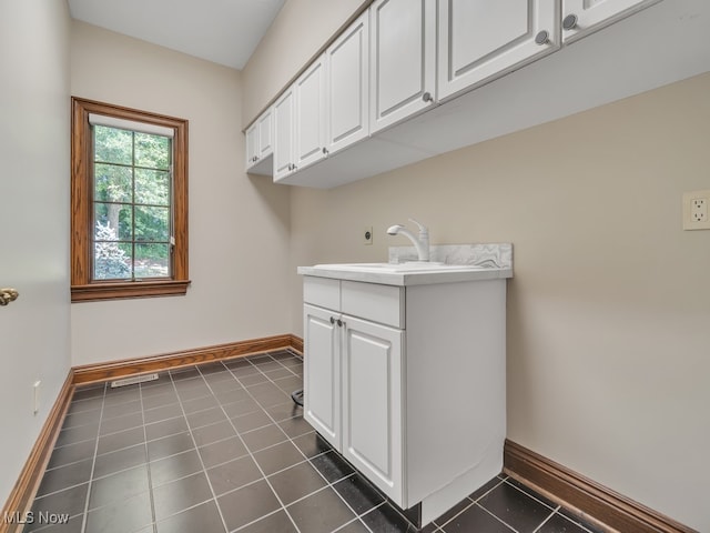 laundry area with dark tile patterned flooring and sink