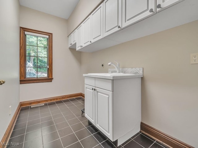 laundry area featuring visible vents, baseboards, a sink, and dark tile patterned flooring