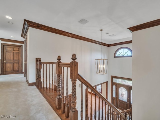 corridor with carpet floors, a high ceiling, an upstairs landing, ornamental molding, and an inviting chandelier