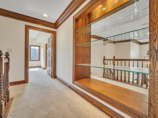 hall featuring carpet, baseboards, and crown molding