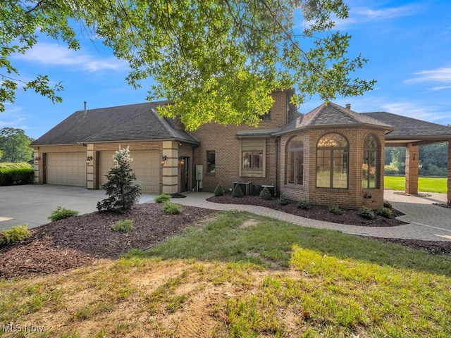 view of front facade with an attached garage, brick siding, driveway, a front lawn, and a chimney