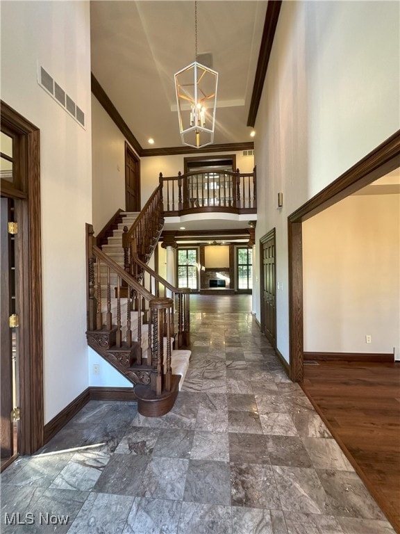 foyer with a high ceiling, crown molding, and a notable chandelier