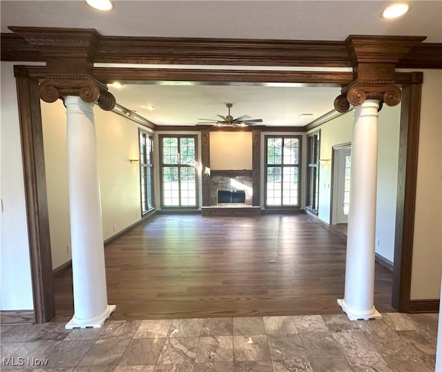 unfurnished living room with ornamental molding, decorative columns, a premium fireplace, wood-type flooring, and ceiling fan