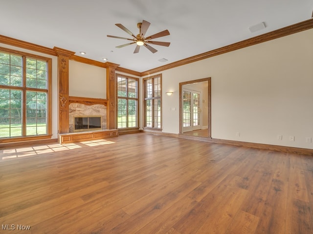 unfurnished living room with ceiling fan, a wealth of natural light, and a fireplace