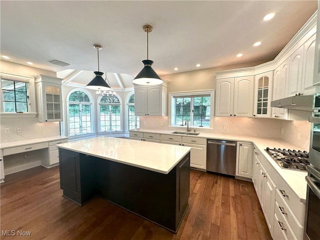 kitchen with appliances with stainless steel finishes, tasteful backsplash, a kitchen island, and dark wood-type flooring