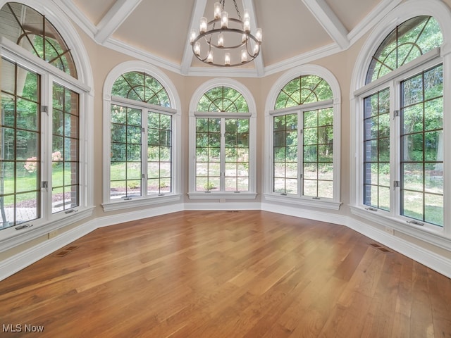 unfurnished sunroom with coffered ceiling, a wealth of natural light, beam ceiling, and a notable chandelier