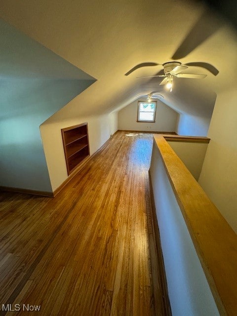 additional living space with built in features, ceiling fan, hardwood / wood-style floors, and lofted ceiling