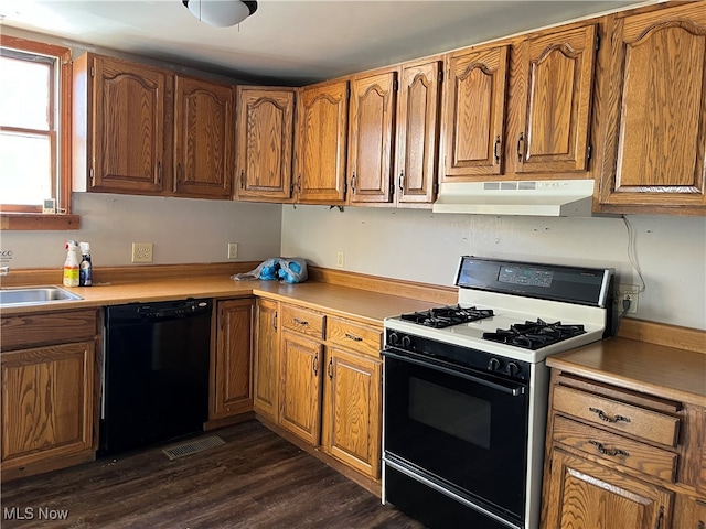 kitchen featuring dark wood-type flooring, sink, black dishwasher, and white gas range oven